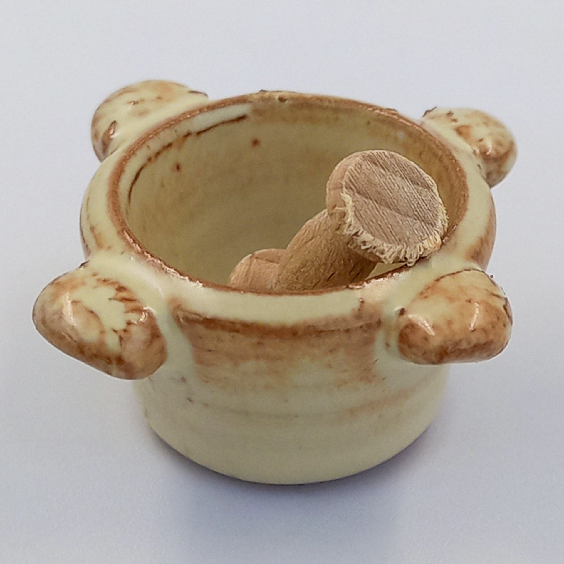 Runder Mörser beigefarben, darin Stößel aus Holz